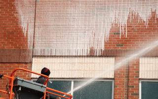 A worker power washes a brick wall in Washington State