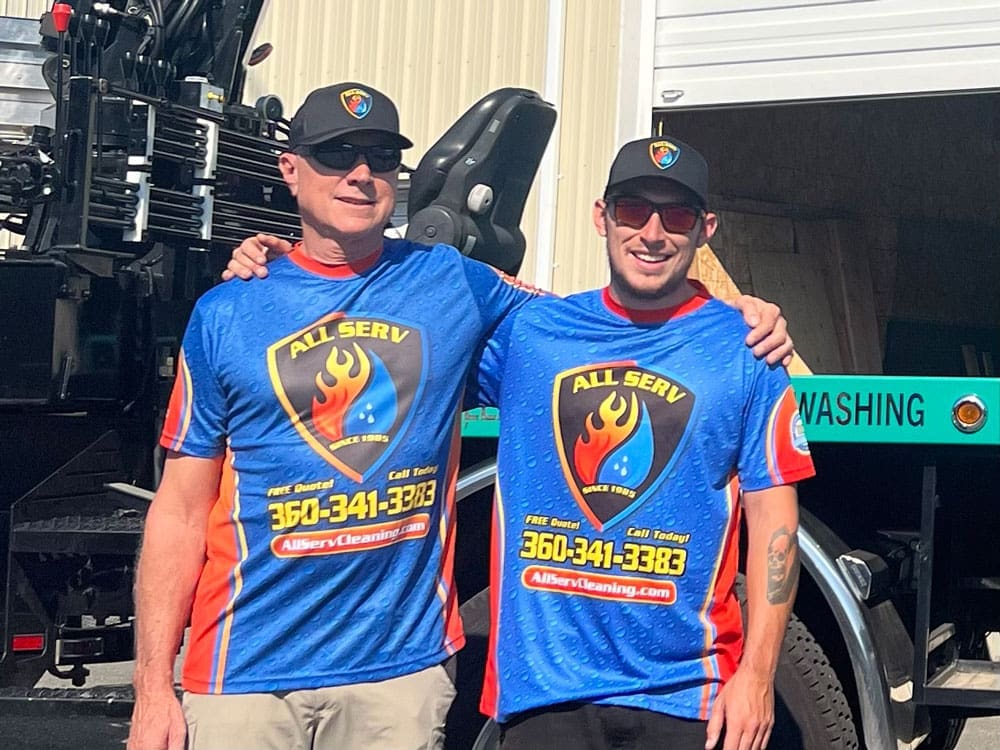 Two men posing in front of a truck.