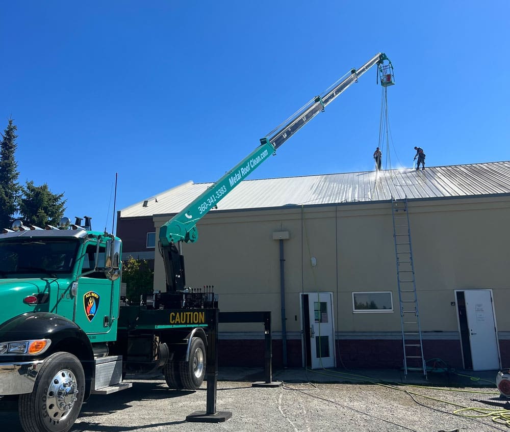 A crane lifts a metal roof off of a building.